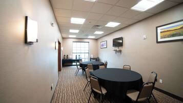 A conference room with a round table, chairs, a projector, and a large window.