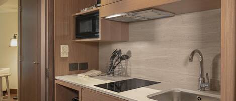 A compact kitchen with a microwave, stove, sink, and wooden cabinets.
