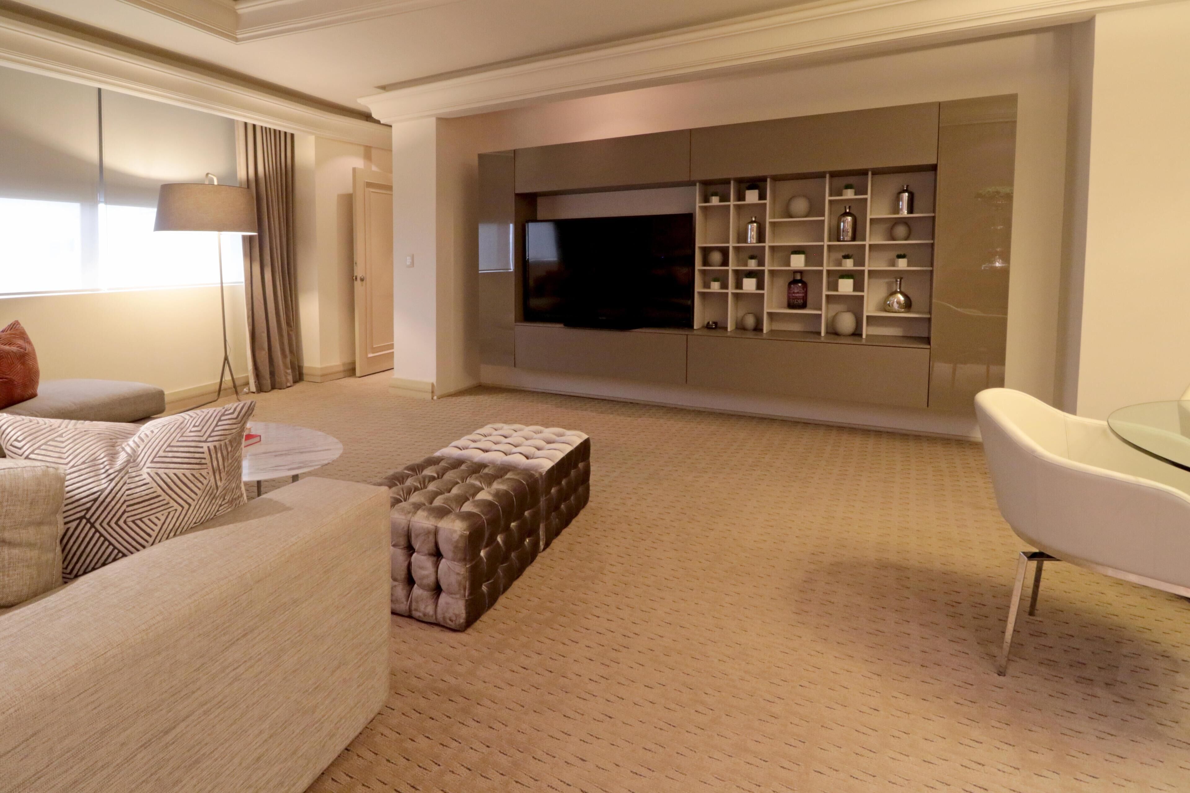 Una sala de estar moderna con un televisor de pantalla plana grande, un sofá, una mesa de centro de vidrio y una mesa de comedor con cubierta de vidrio.