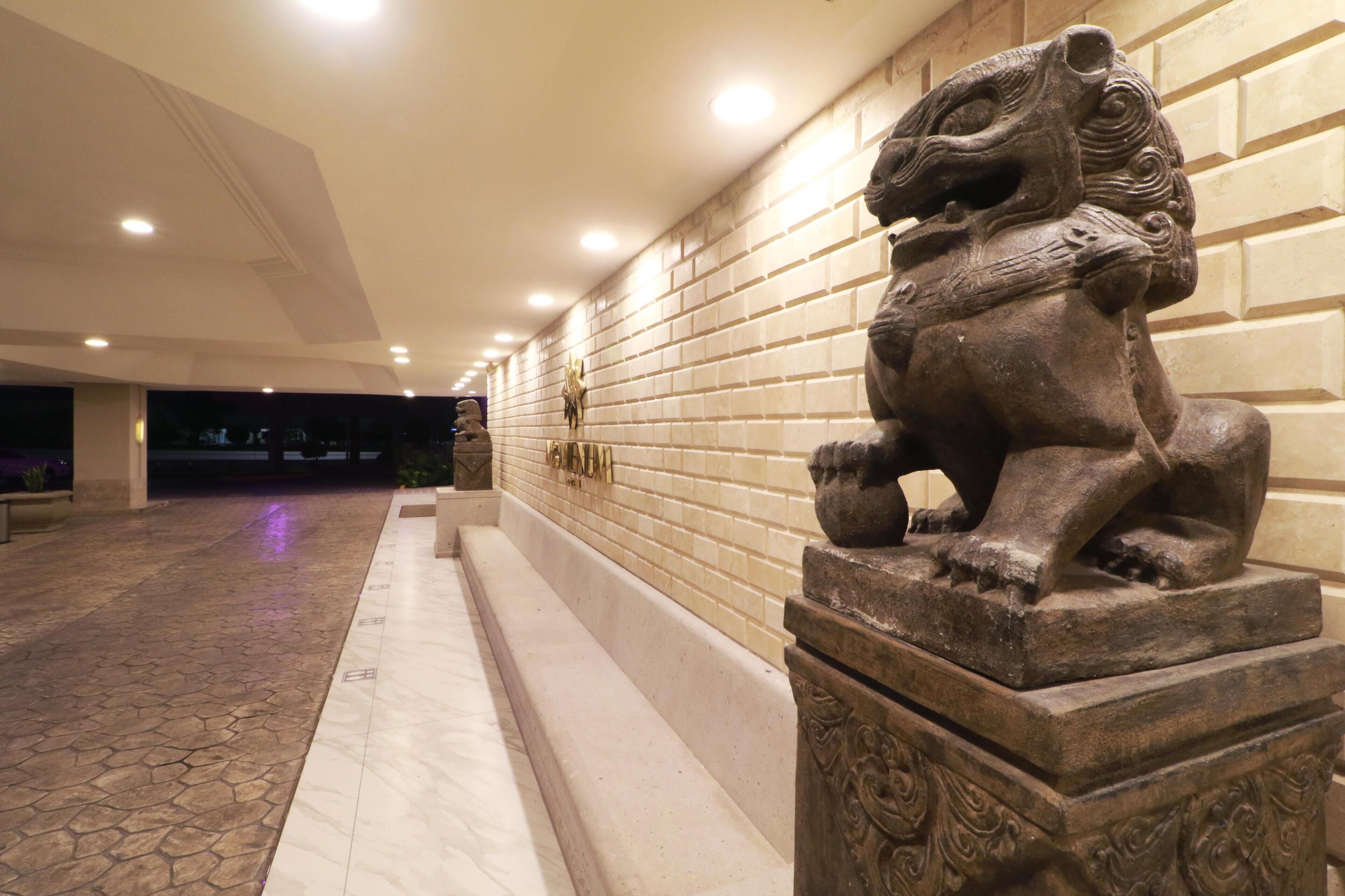 Un pasillo con una estatua de león, paredes de azulejos y un suelo estampado.