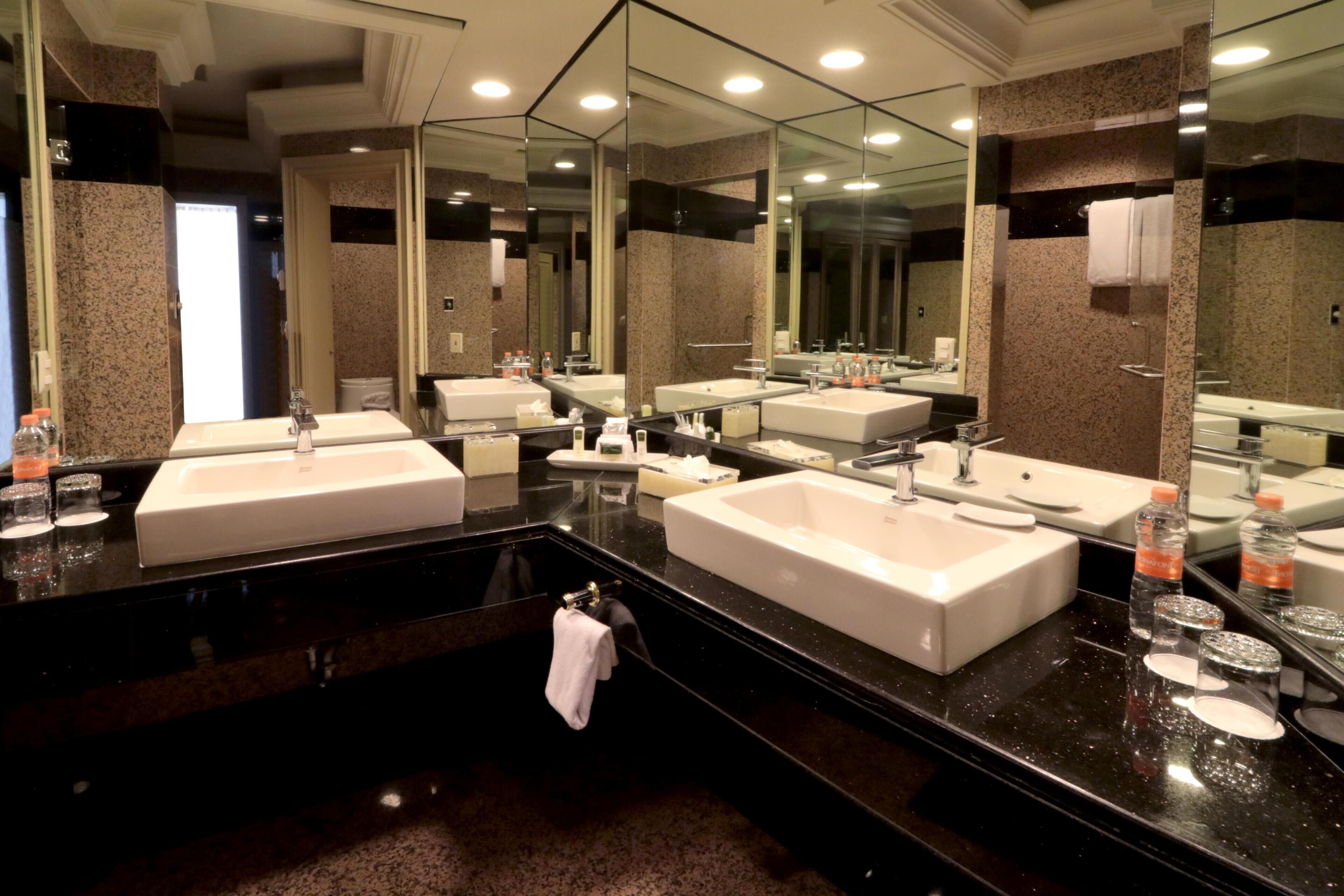 A modern bathroom with two sinks, a large mirror, and a towel rack.