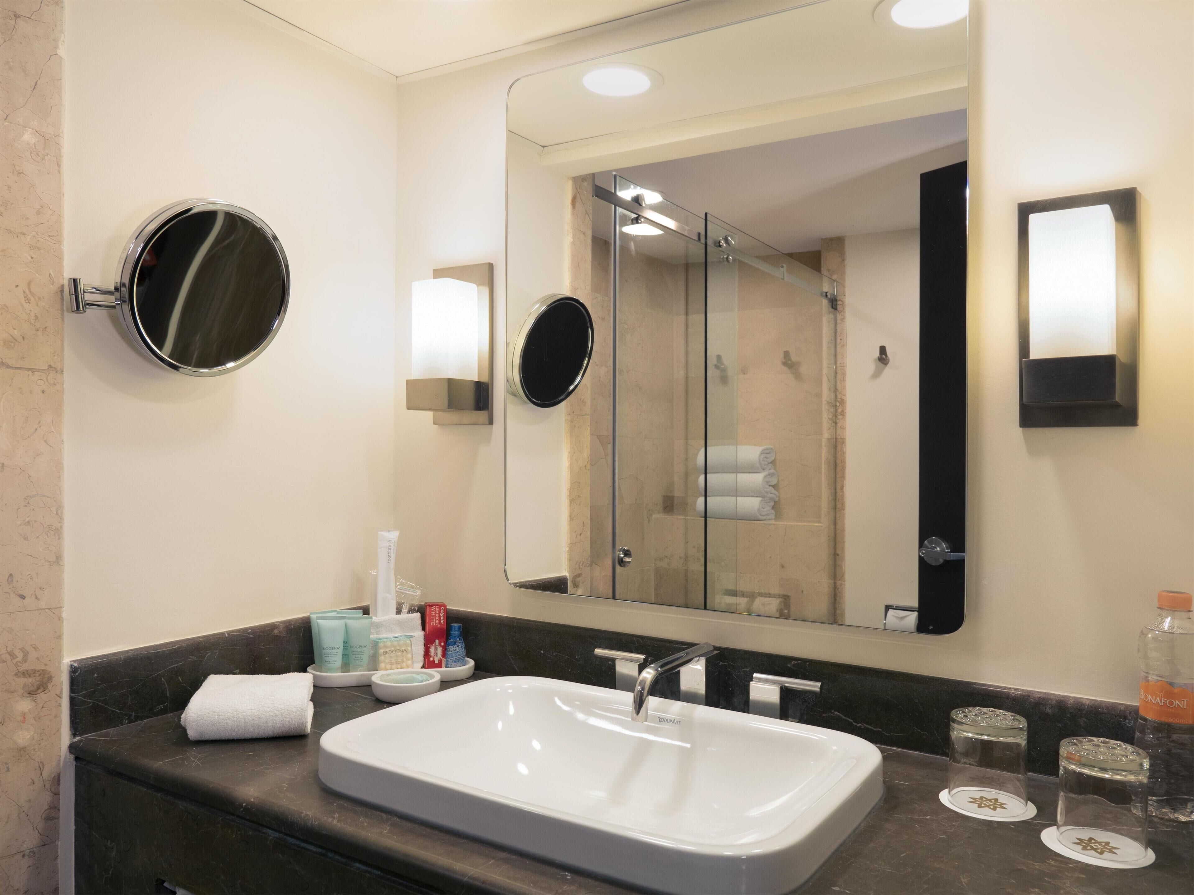 Une salle de bain moderne avec un grand miroir, un lavabo et une douche à parois de verre.
