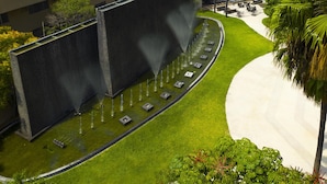 A landscaped area with a water feature, seating, and a curved pathway. - MS Milenium Monterrey, Curio Collection by Hilton (San Pedro Garza García)