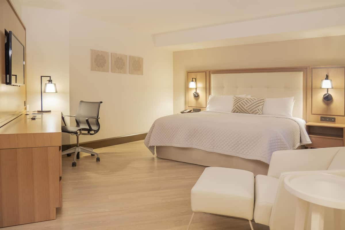 Ett hotellrum med en säng, ett skrivbord, en stol och sängbord.