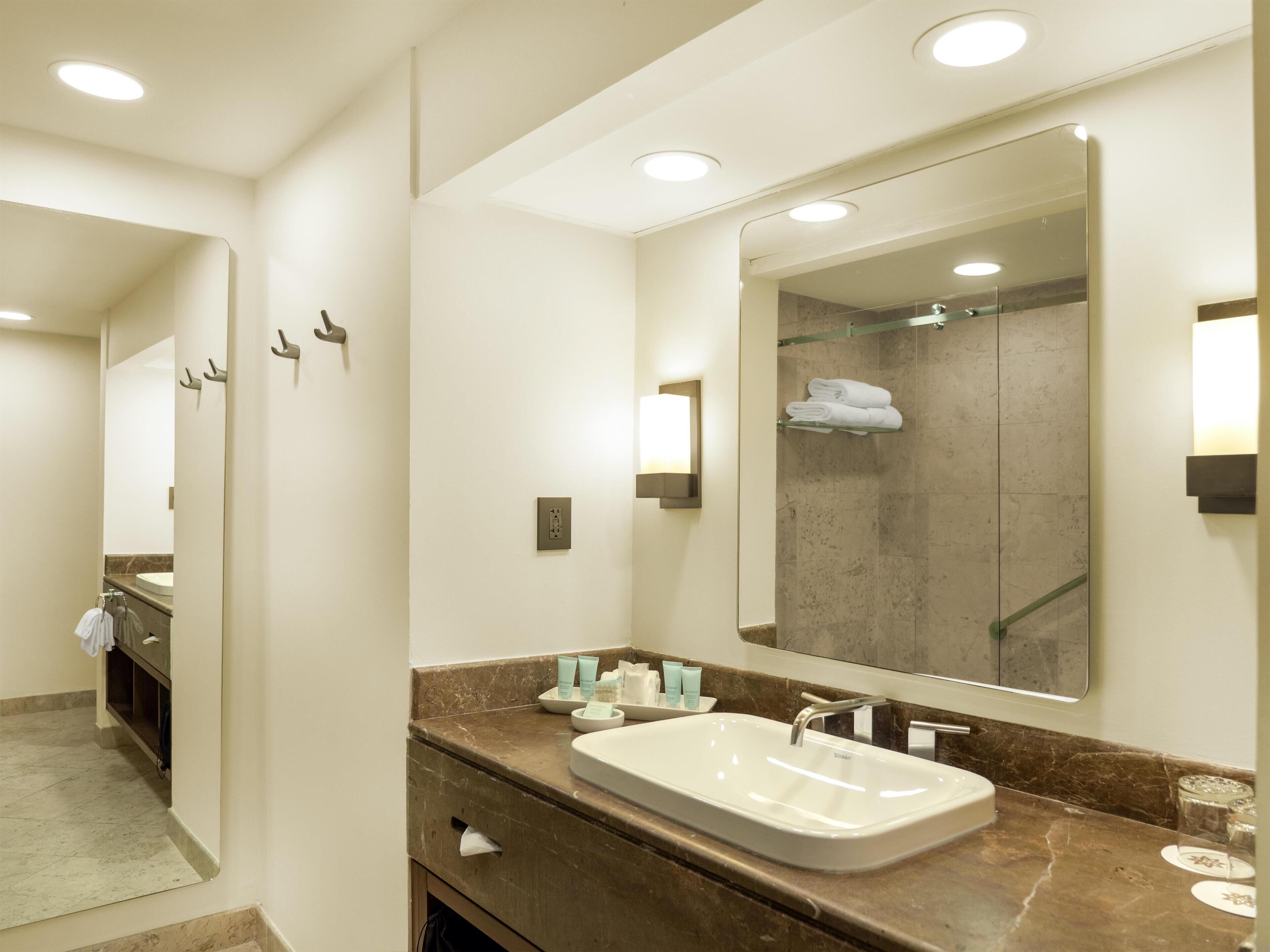 A modern bathroom with a large mirror, a sink, and a shower area.