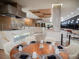 Un comedor moderno con mostrador de mármol, sillas blancas y una mesa redonda central dispuesta para una comida.
