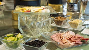 Een buffet met diverse soorten eten, waaronder gesneden fruit, noten en vlees.