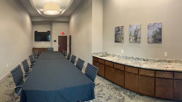 A conference room with a long table, chairs, a TV, and artwork on the wall. - Hyatt Select Valdosta (Valdosta)