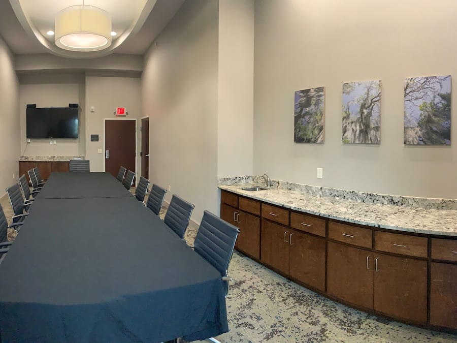 A conference room with a long table, chairs, a TV, and artwork on the wall.