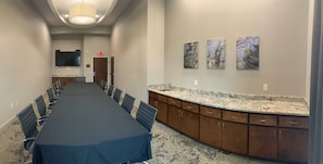 A conference room with a long table, chairs, a TV, and artwork on the wall. - Hyatt Select Valdosta (Valdosta)