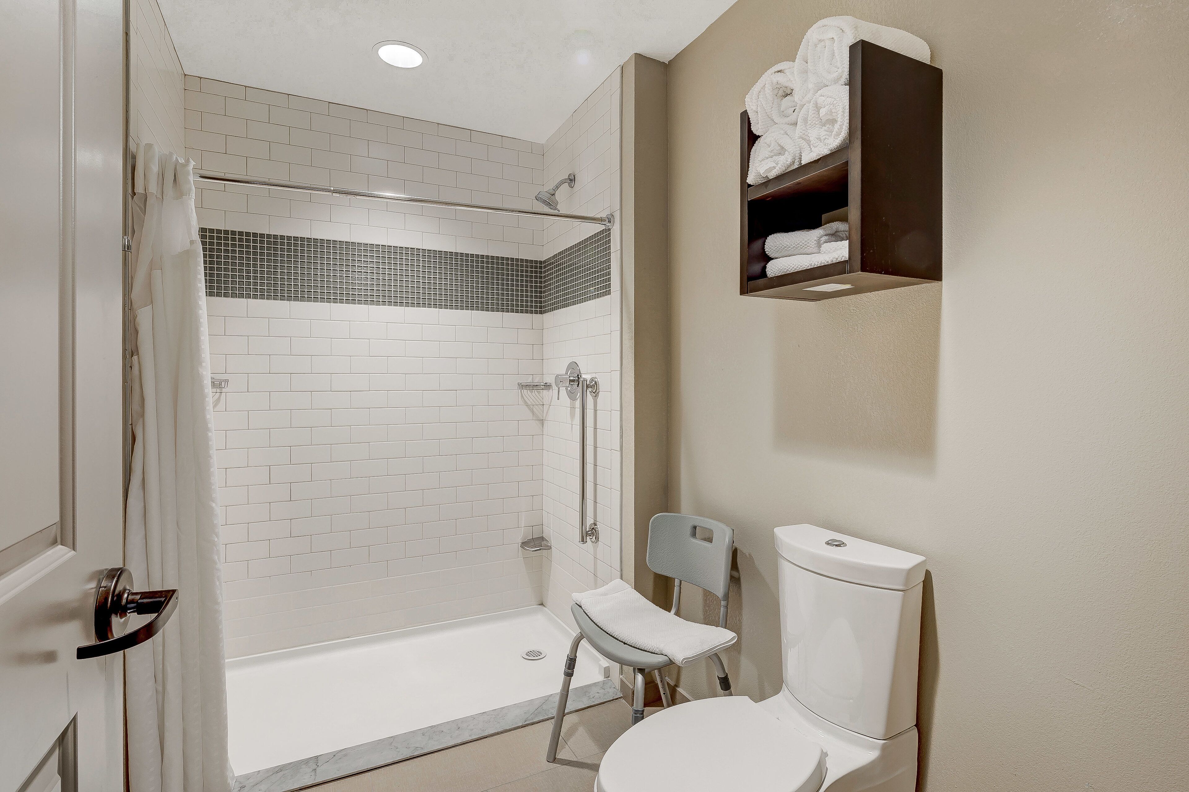 A modern bathroom with a walk-in shower, a toilet, and a towel rack.