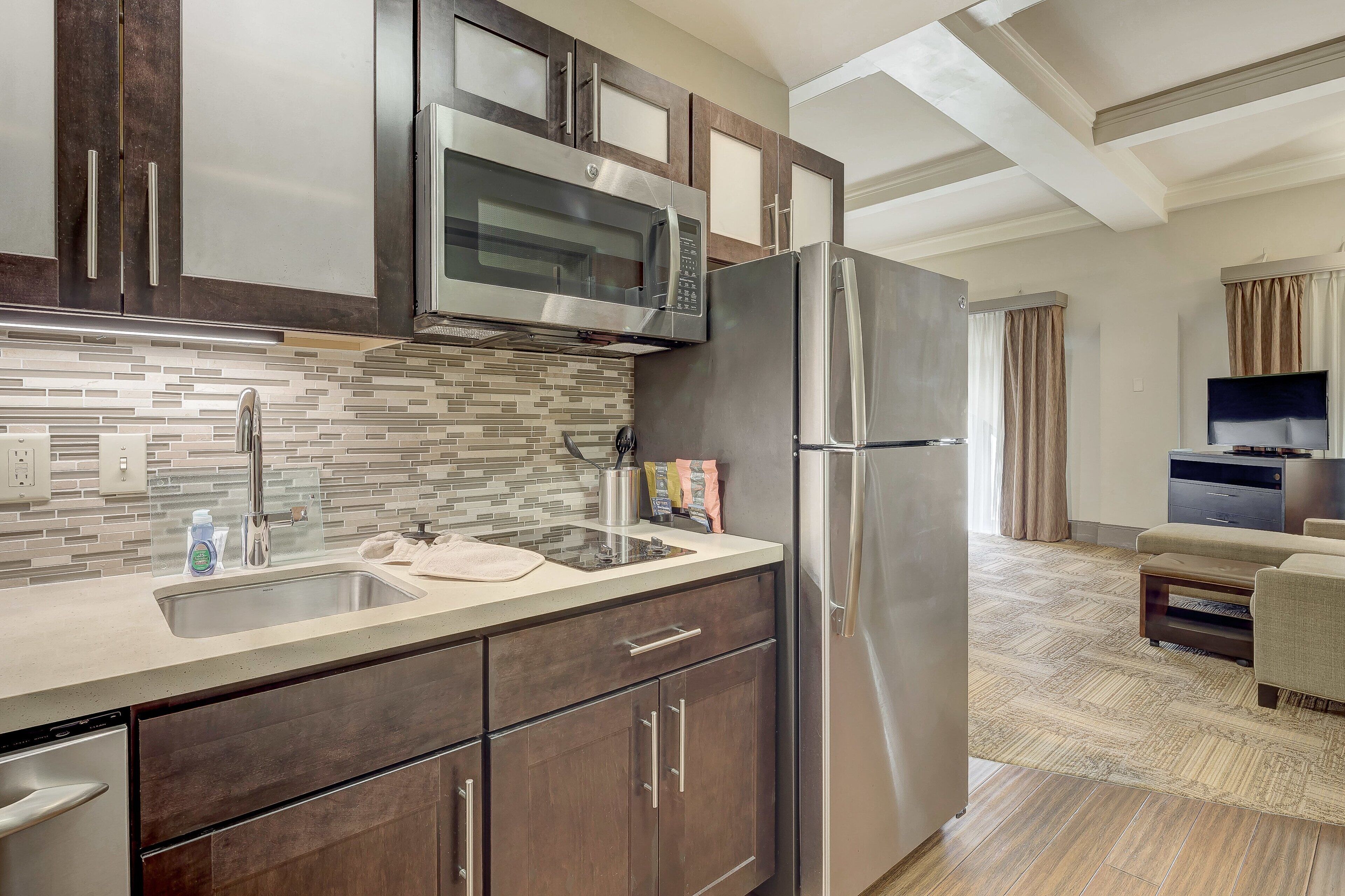 Una cocina moderna con electrodomésticos de acero inoxidable, salpicadero de azulejos y armarios de madera.