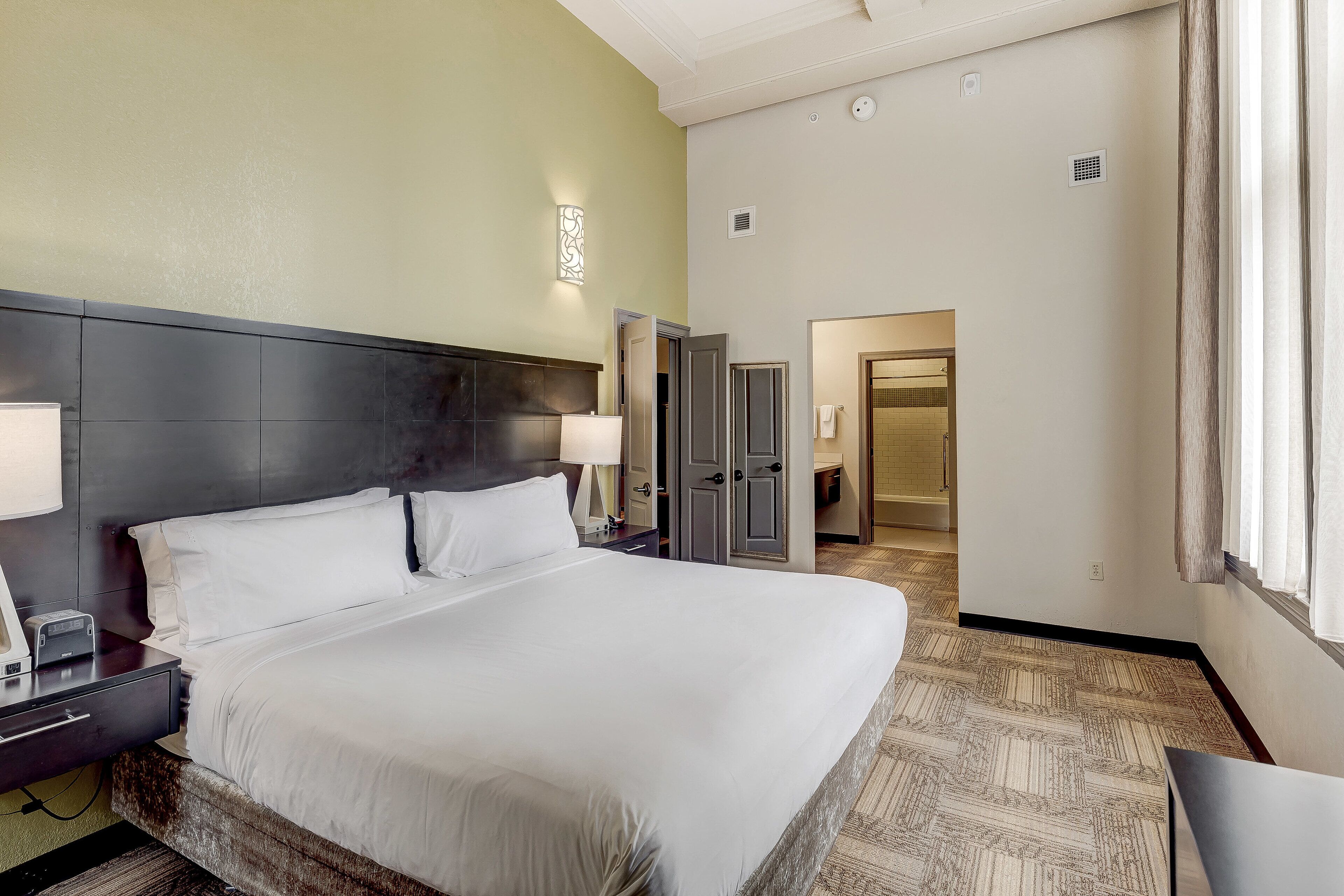Una camera d'albergo con un letto grande, comodini, una scrivania e un armadio.
