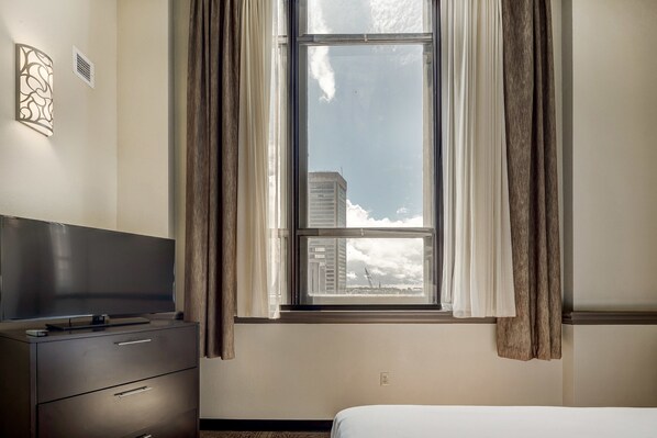 A hotel room with a bed, a dresser, a flat-screen TV, and a window with curtains. - Staybridge Suites Baltimore - Inner Harbor by IHG (Baltimore)