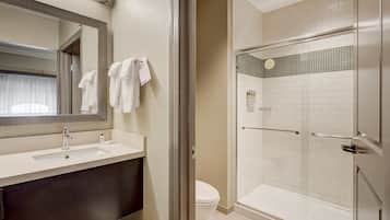 A bathroom with a sink, mirror, and a glass-enclosed shower area.