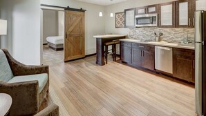 A modern kitchen with wooden cabinets, a stainless steel refrigerator, and a large island with bar stools.
