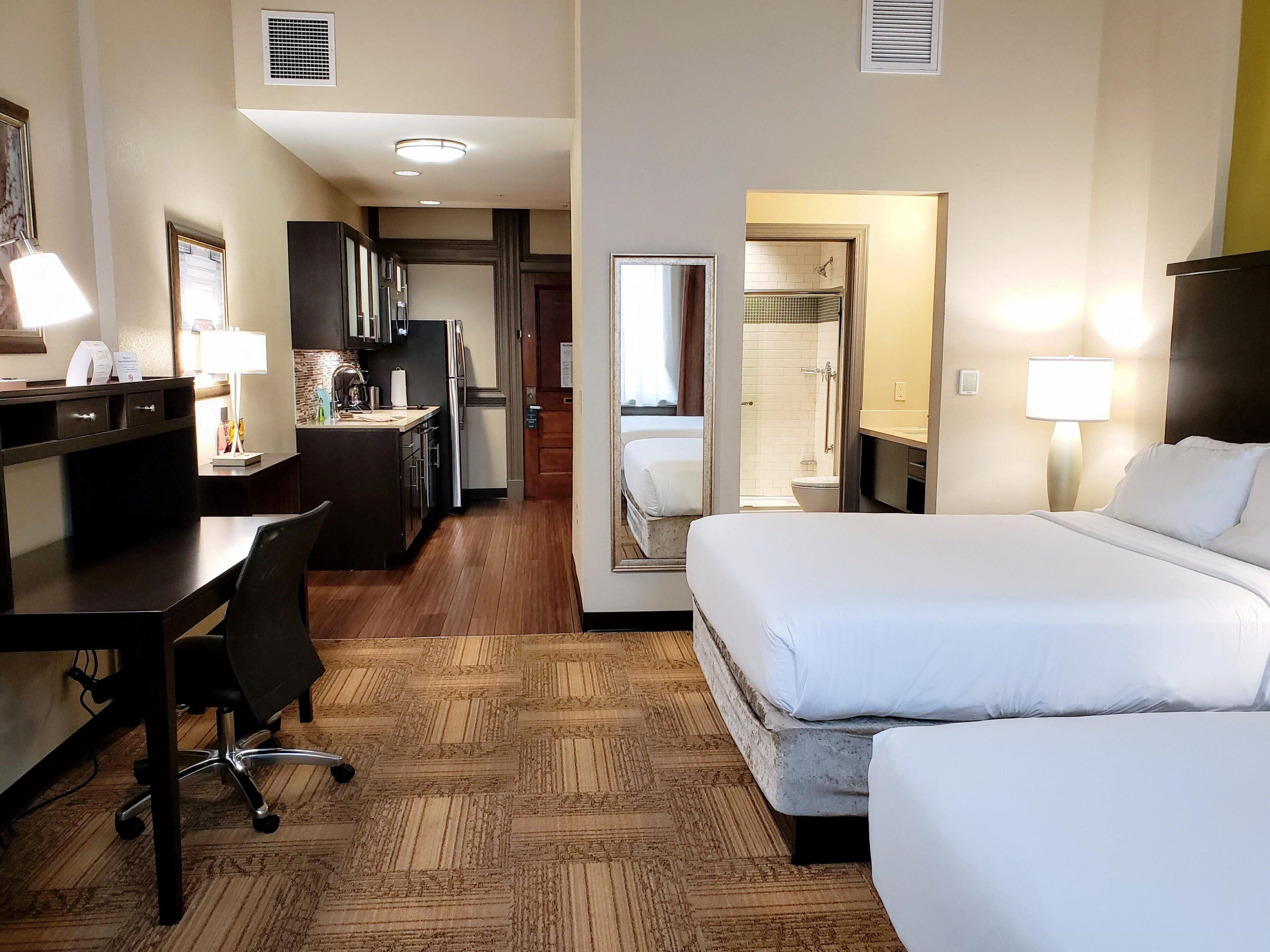 Une chambre d’hôtel équipée d’un bureau, de deux lits, d’une douche et d’une kitchenette.