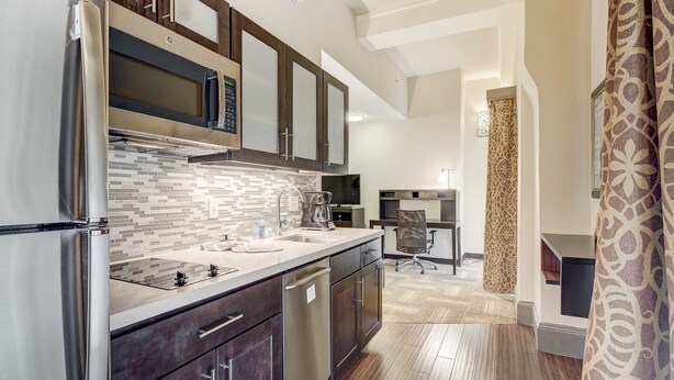 A modern kitchen with stainless steel appliances, dark wooden cabinets, and a tiled backsplash. - Staybridge Suites Baltimore - Inner Harbor by IHG (Baltimore)