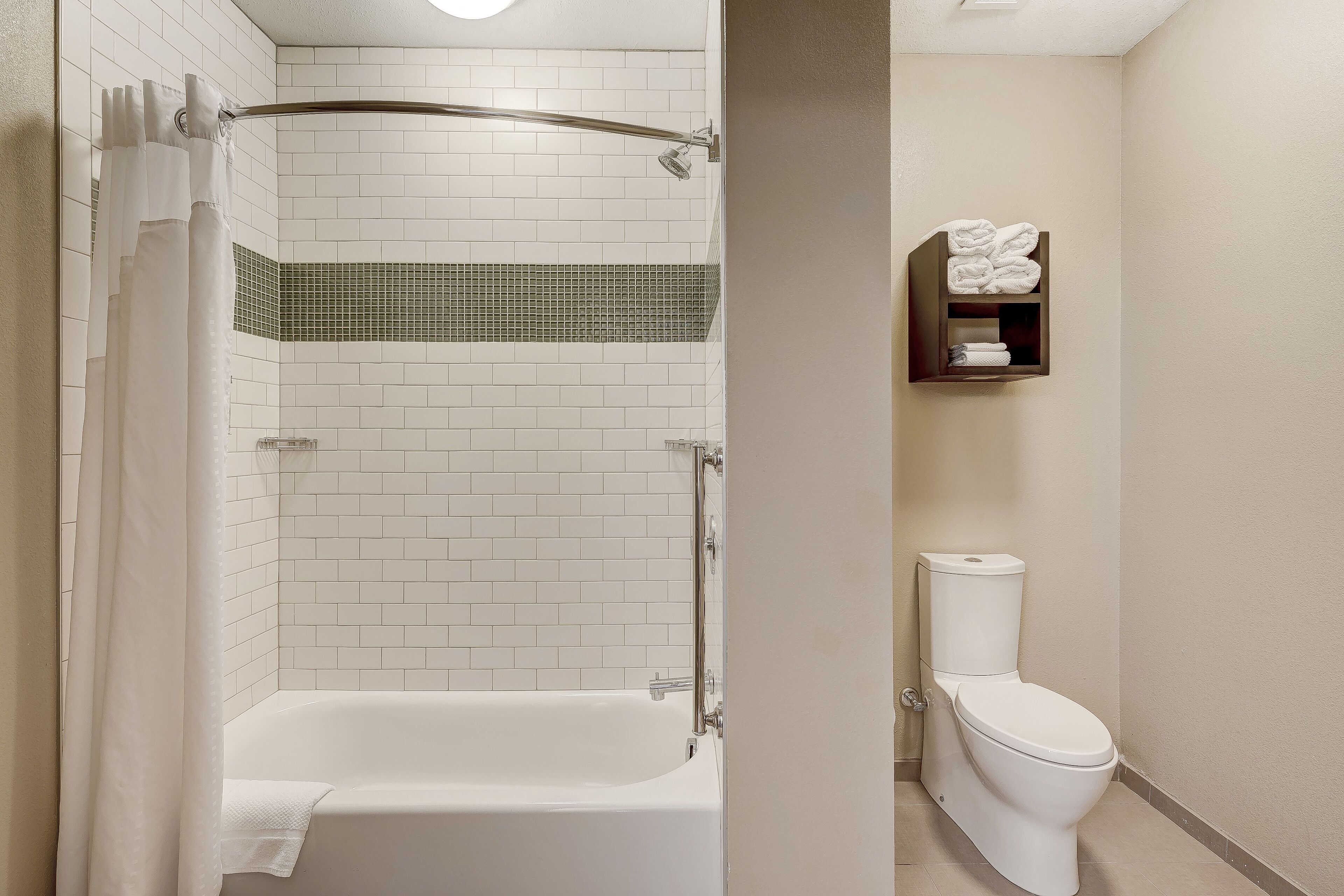 A modern bathroom with a white bathtub, a shower, and a toilet.