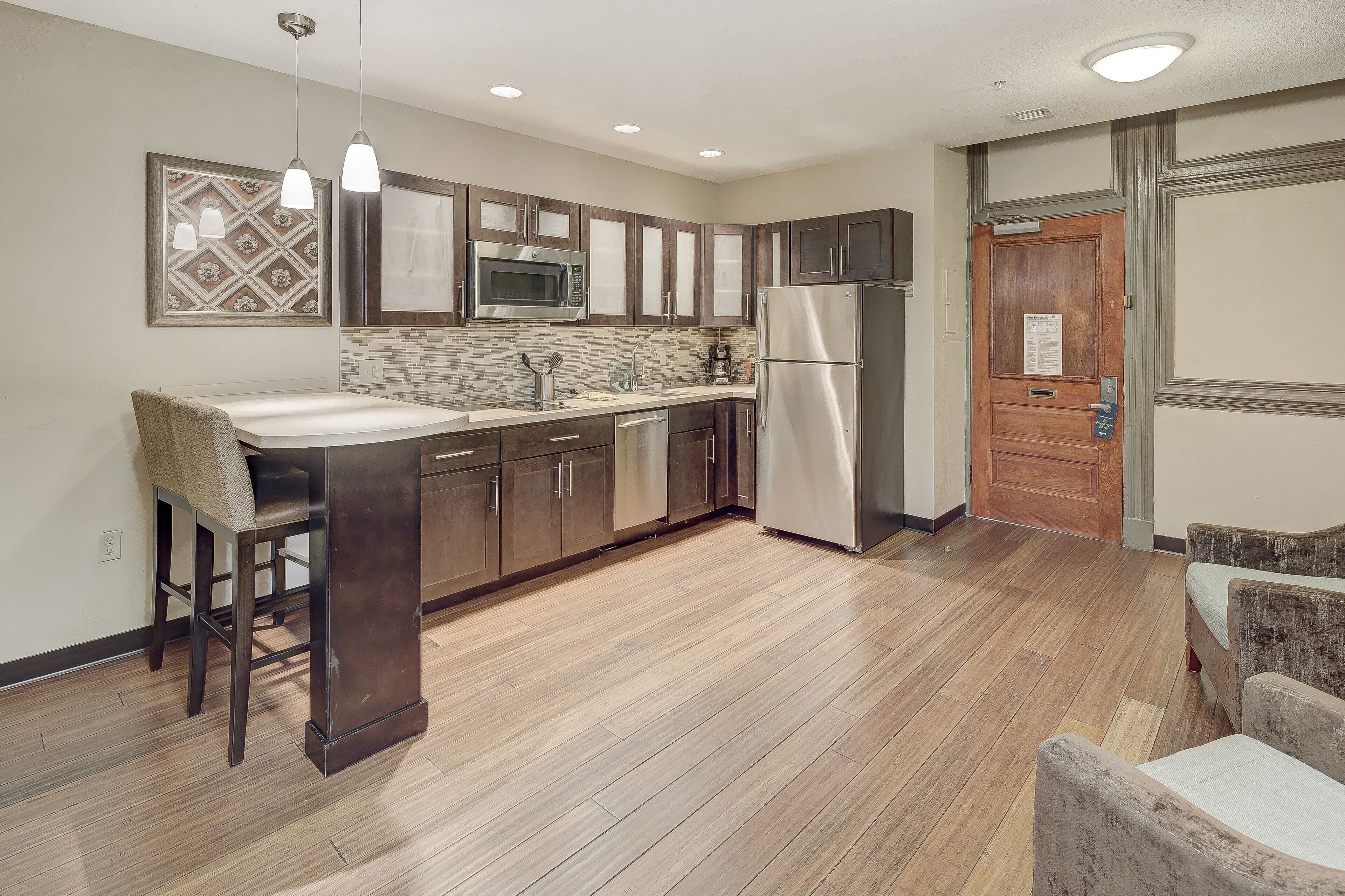 A modern kitchen with wooden cabinets, stainless steel appliances, and a tiled backsplash.