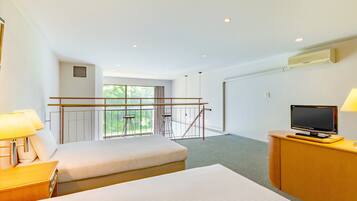 Une chambre d’hôtel avec deux lits, un bureau avec un ordinateur, une télévision et un balcon avec une balustrade.