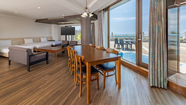 Een moderne hotelkamer met een grote eettafel, comfortabele zitplaatsen, een bank en een televisie.
