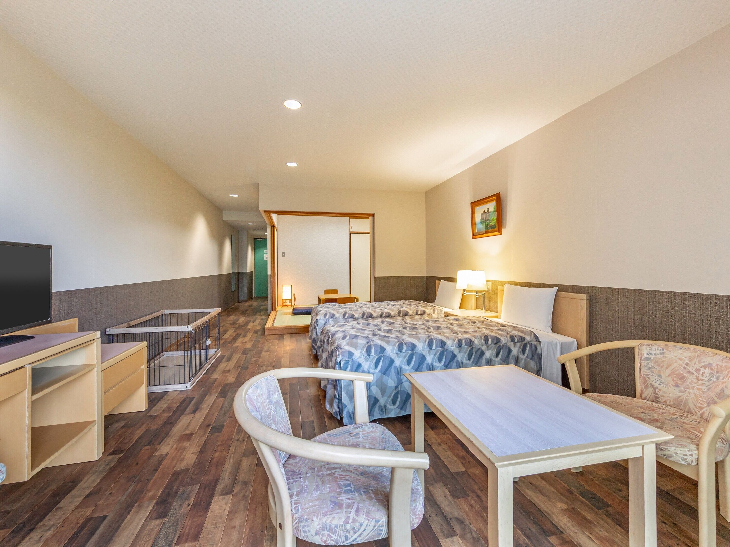 A hotel room with a bed, desk, chair, and a television.