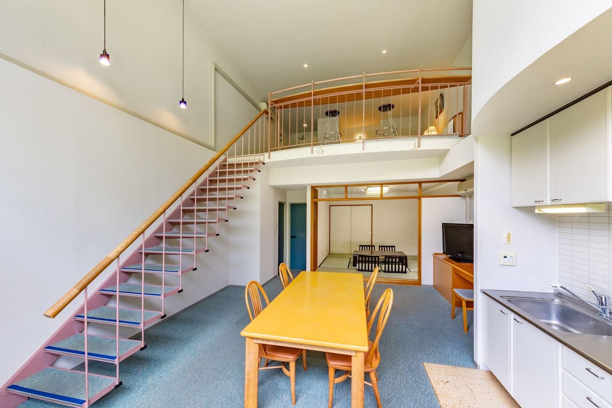 Un interior moderno con escalera, comedor, cocina y balcón.
