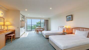 A hotel room with two beds, a desk, a chair, a balcony with a view, and a painting on the wall.
