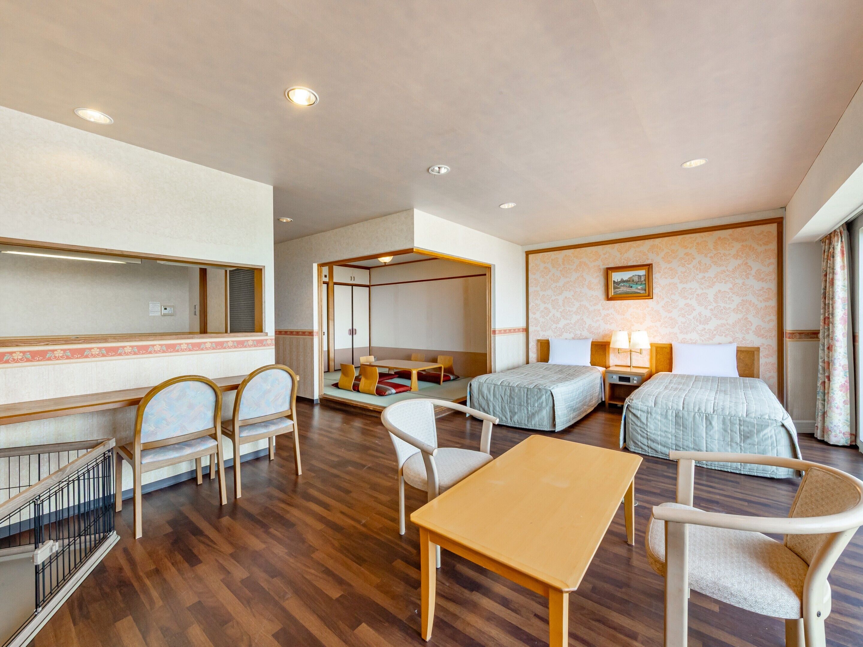 A hotel room with a bed, two bedside tables, a desk, a chair, a sofa, and a small balcony.