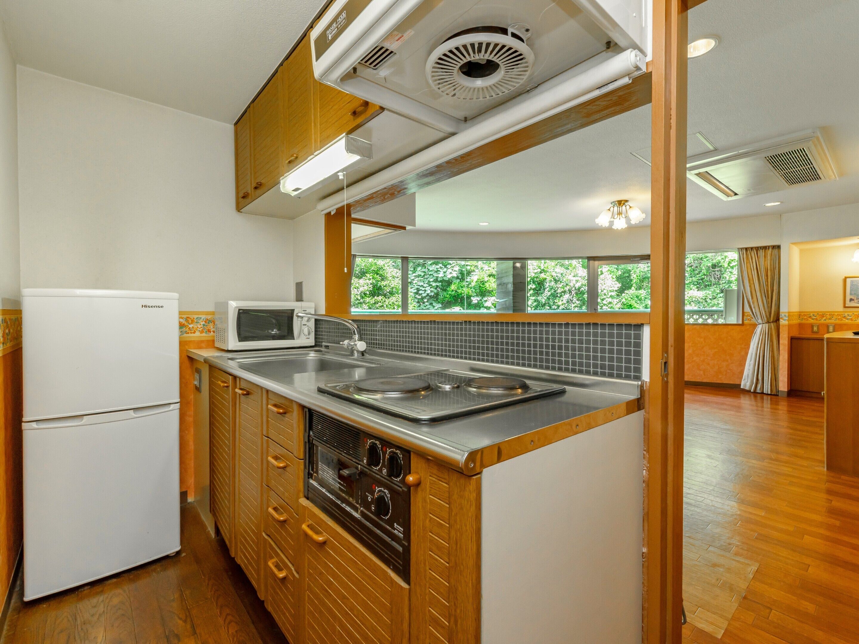 A compact kitchen with a refrigerator, microwave, sink, and wooden cabinets.