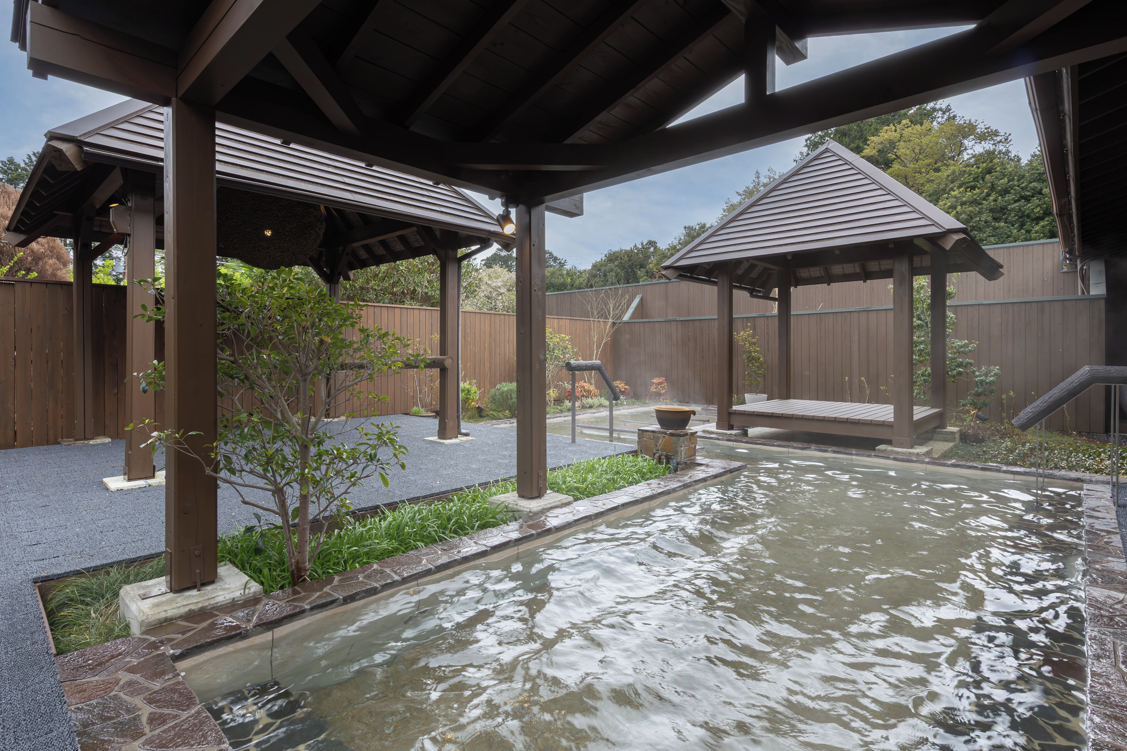 A spa area with a hot spring, wooden pergolas, and a wooden fence.