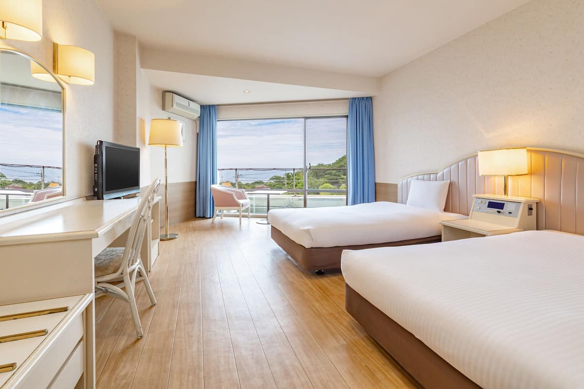 Een hotelkamer met een bed, bureau, stoel, televisie en uitzicht op de omgeving.