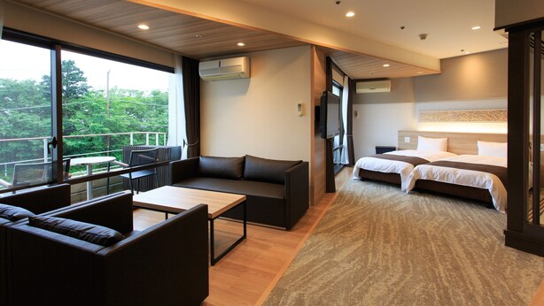 A modern hotel room with a balcony, a sofa, a bed, and a desk. - Wan Wan Paradise Izukogen (Ito)
