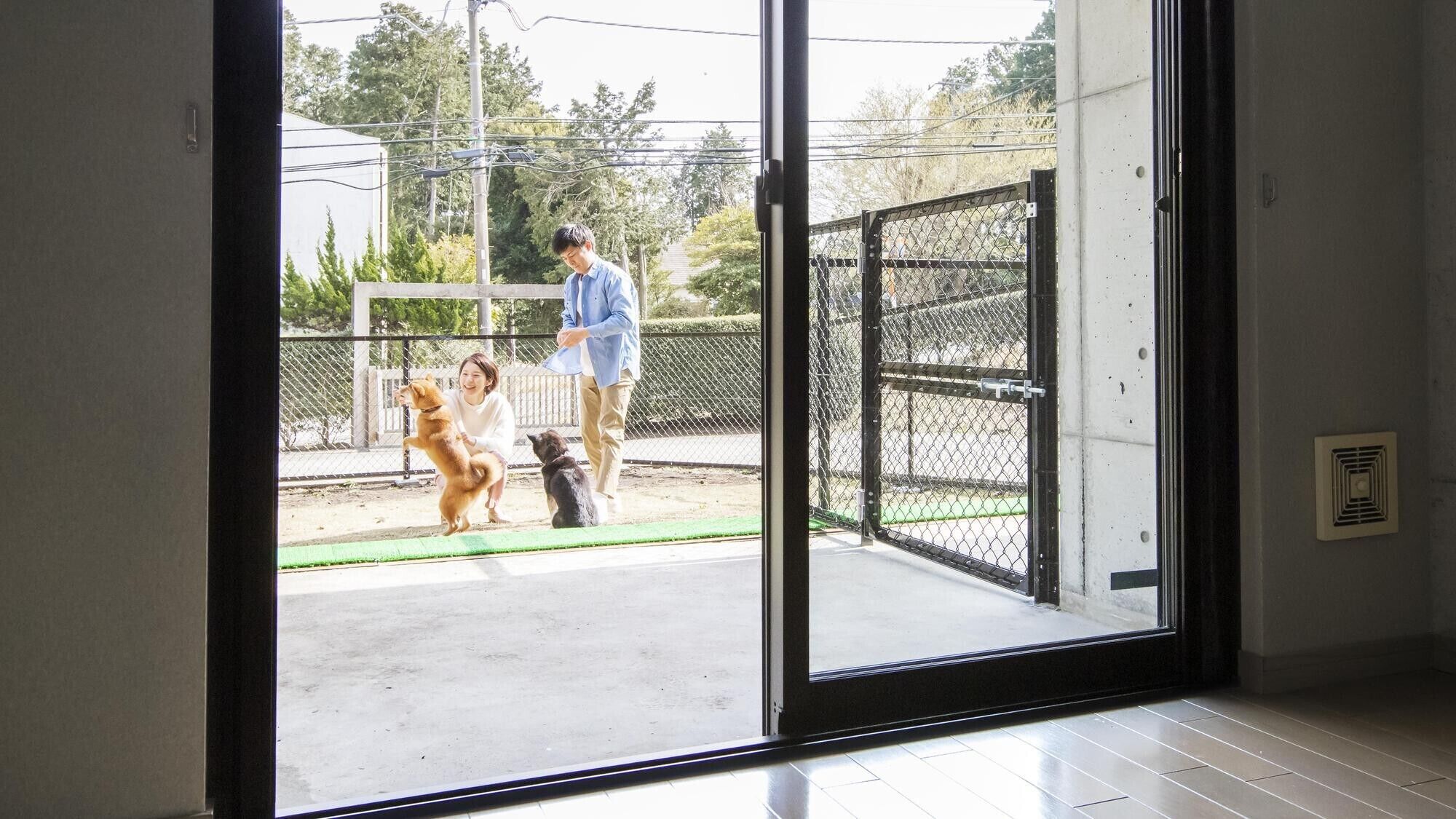 A room with a sliding glass door leading to an outdoor area with a chain-link fence.