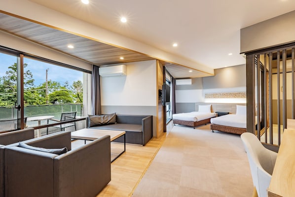 A modern hotel room with a balcony, a sofa, a bed, and a TV. - Wan Wan Paradise Izukogen (Ito)
