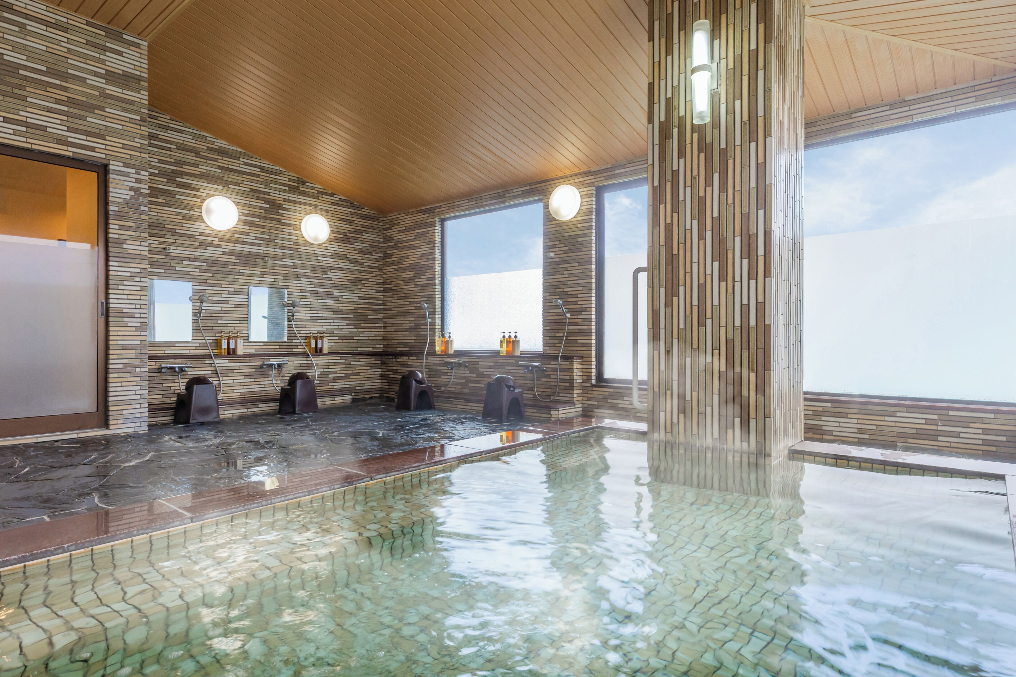 A modern indoor swimming pool with a tiled floor and a wooden ceiling.
