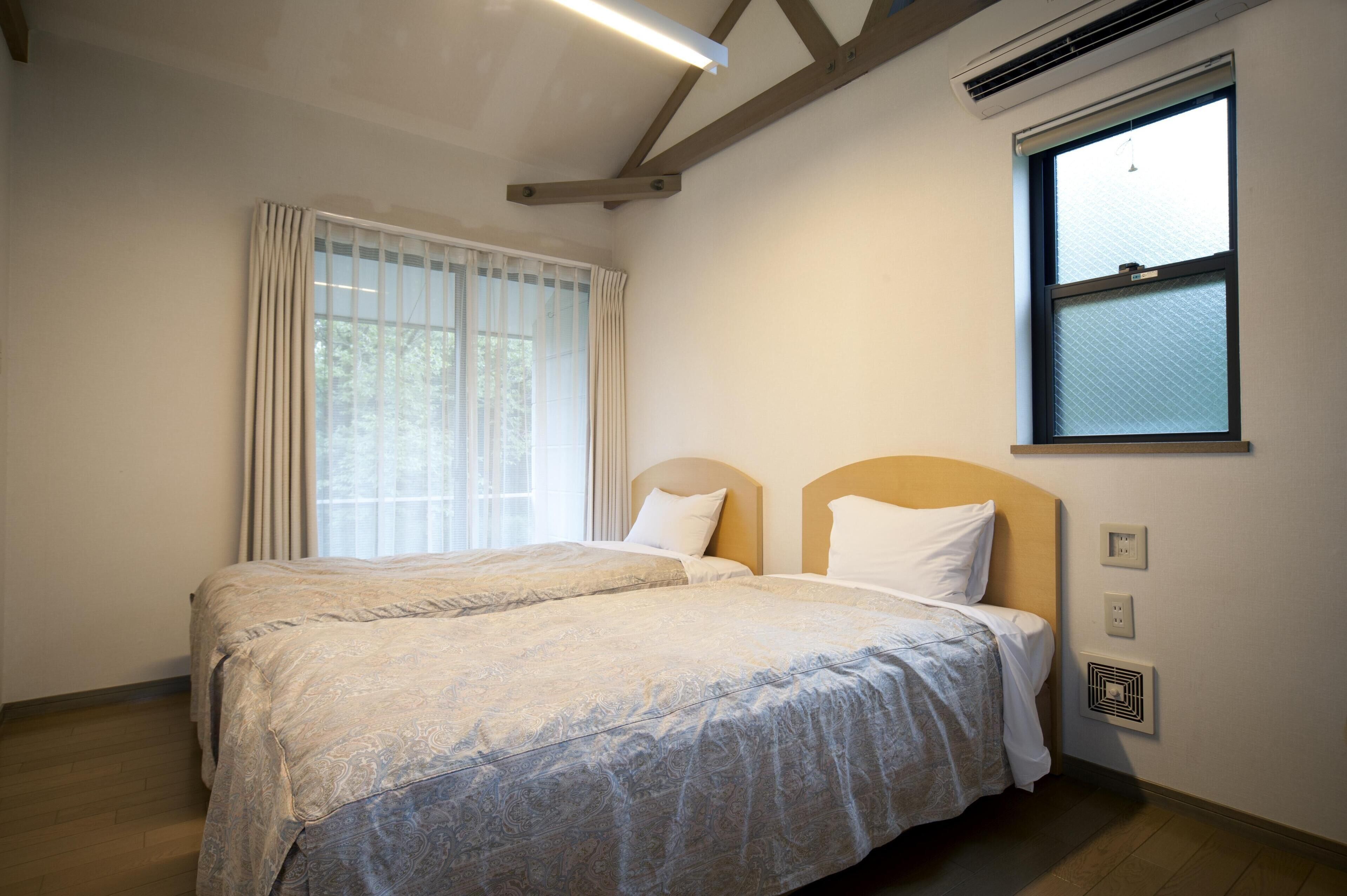 A double bed with a headboard, a window with blinds, and a ceiling fan.