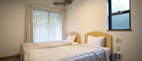 A double bed with a headboard, a window with blinds, and a ceiling fan.