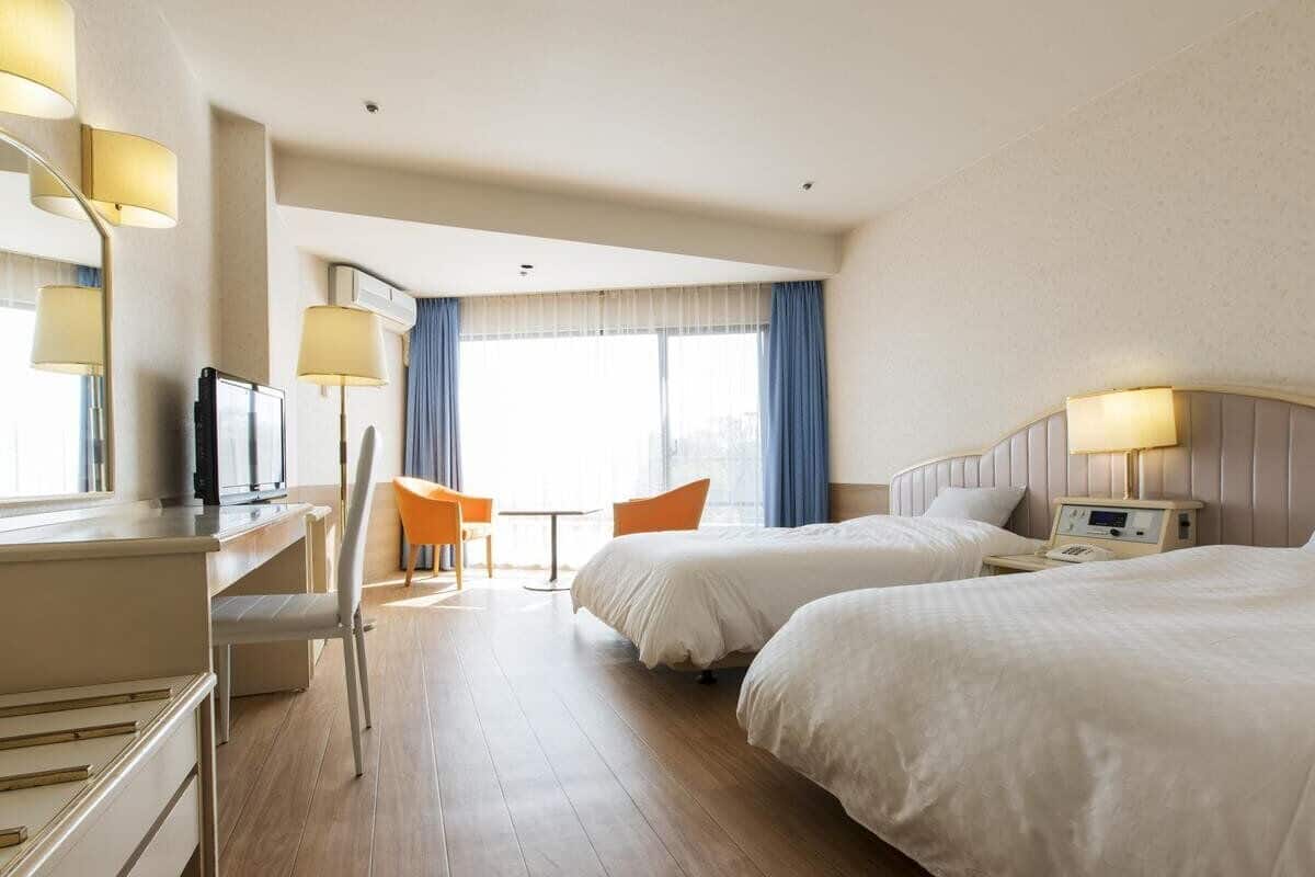 Een hotelkamer met twee bedden, een bureau, een stoel en een televisie.