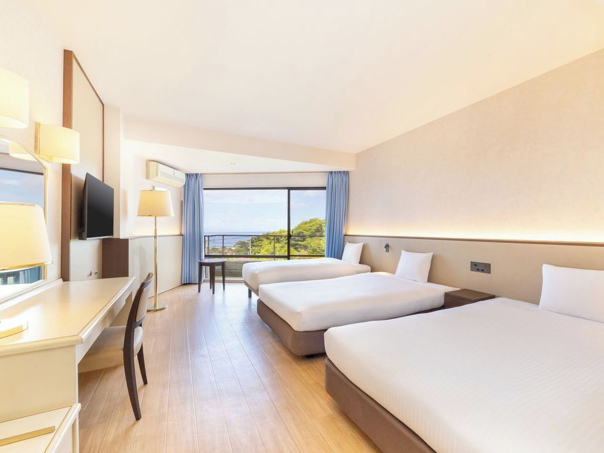 Une chambre d’hôtel avec deux lits, un bureau, une télévision et une vue sur l’extérieur.