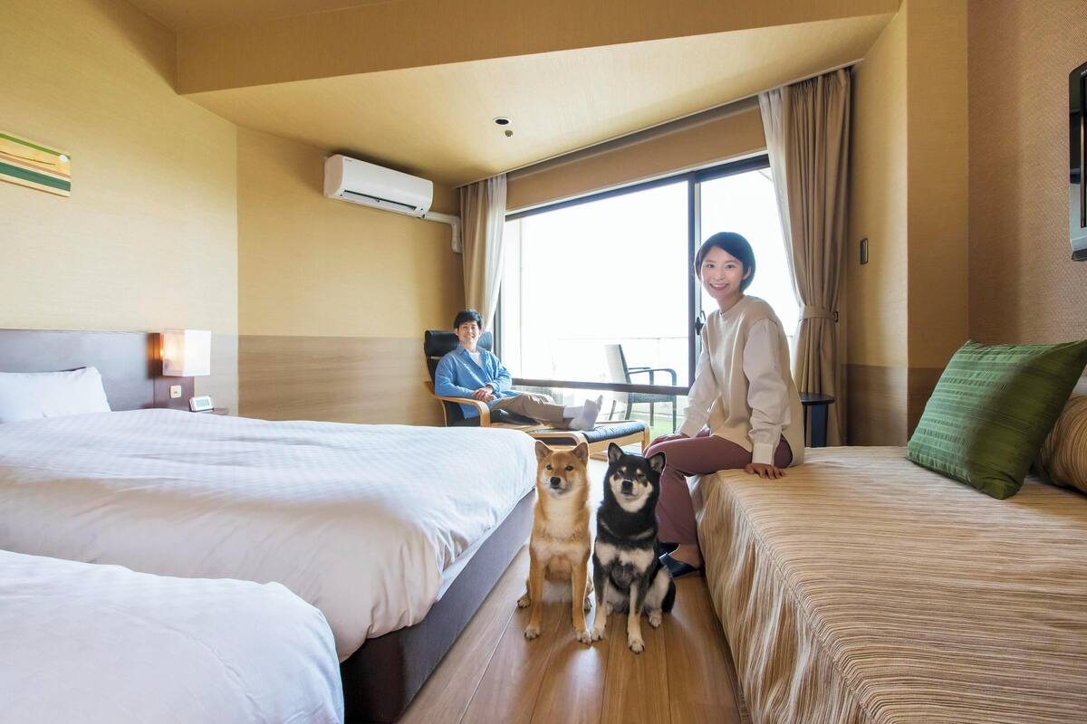 Een hotelkamer met twee bedden, een bank en een raam met gordijnen.