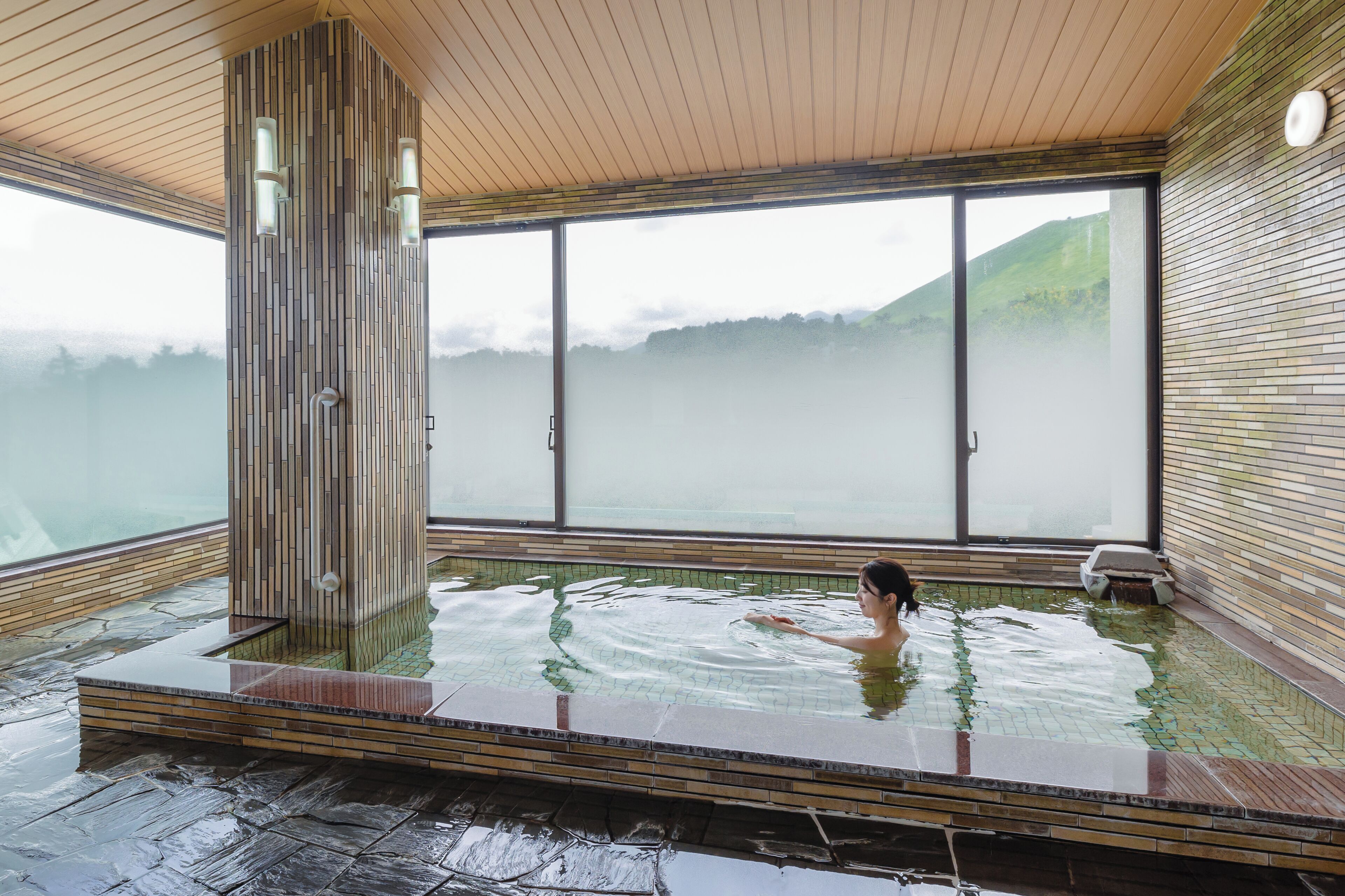 Una gran piscina interior amb vistes a un paisatge de muntanyes a través de grans finestres.