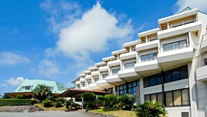 A multi-story hotel with balconies, a covered entrance, and a clear sky. - Wan Wan Paradise Izukogen (Ito)