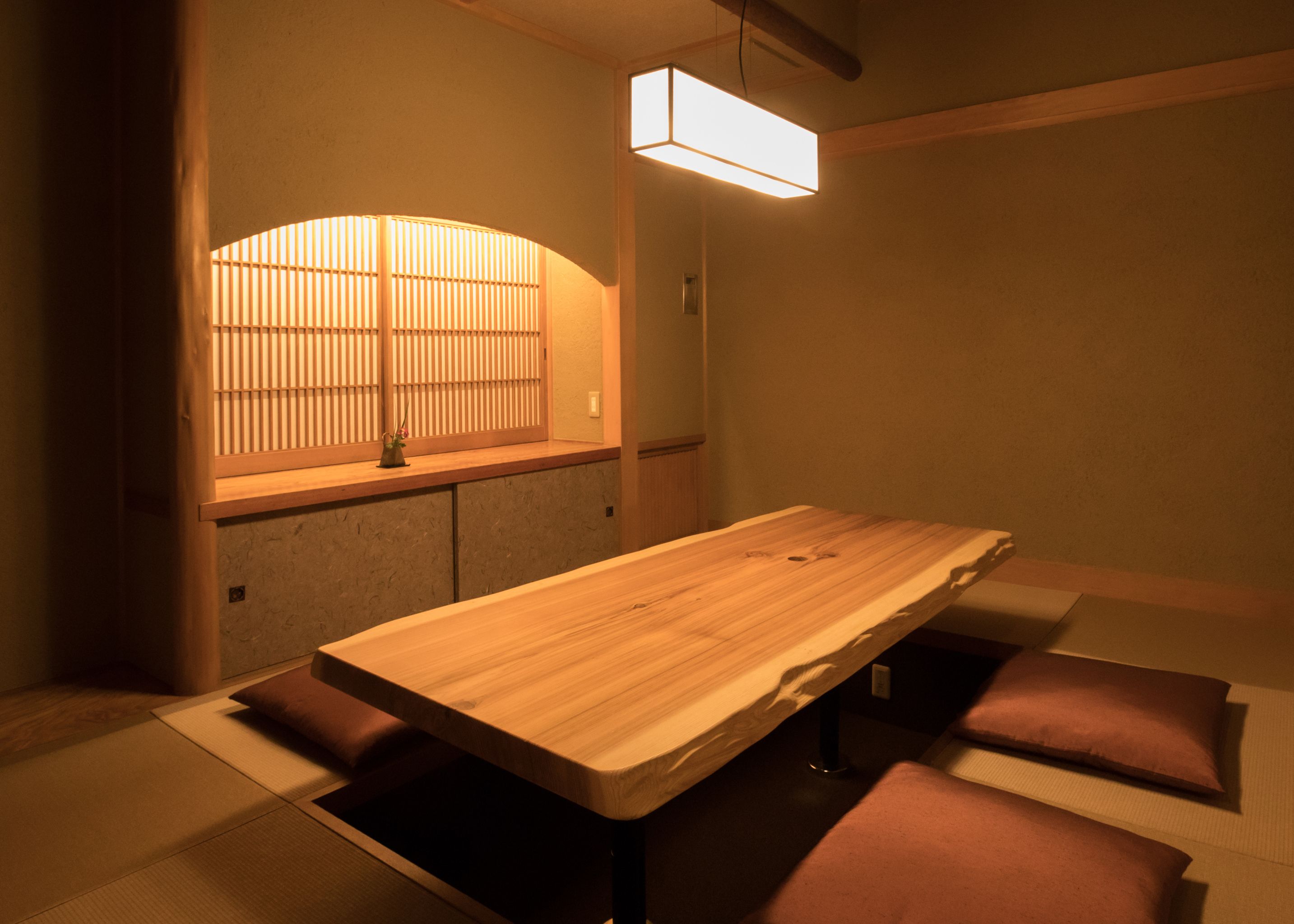 A traditional Japanese-style room with tatami flooring, a low wooden table, and a shoji screen.
