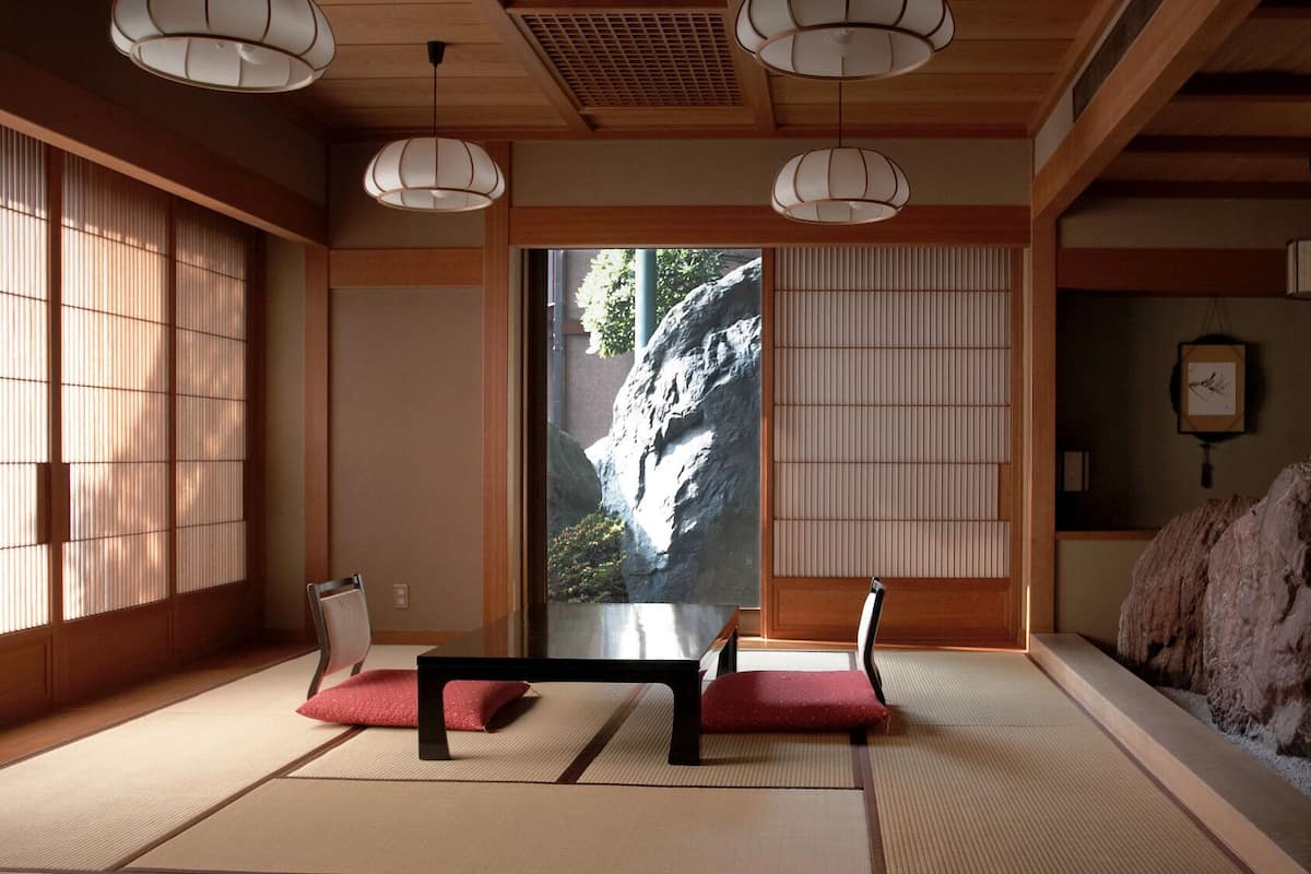 Une pièce de style japonais traditionnel, avec un sol recouvert de tatamis, des paravents en papier de riz (shoji) et un arrangement de rochers.