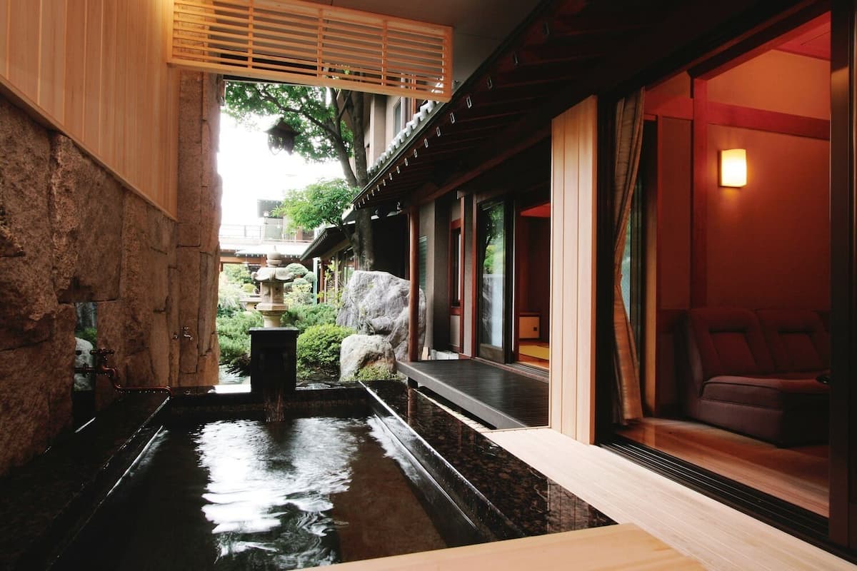 Un intérieur de style japonais traditionnel, avec un bassin à carpes koï, un plancher en bois et des portes coulissantes.