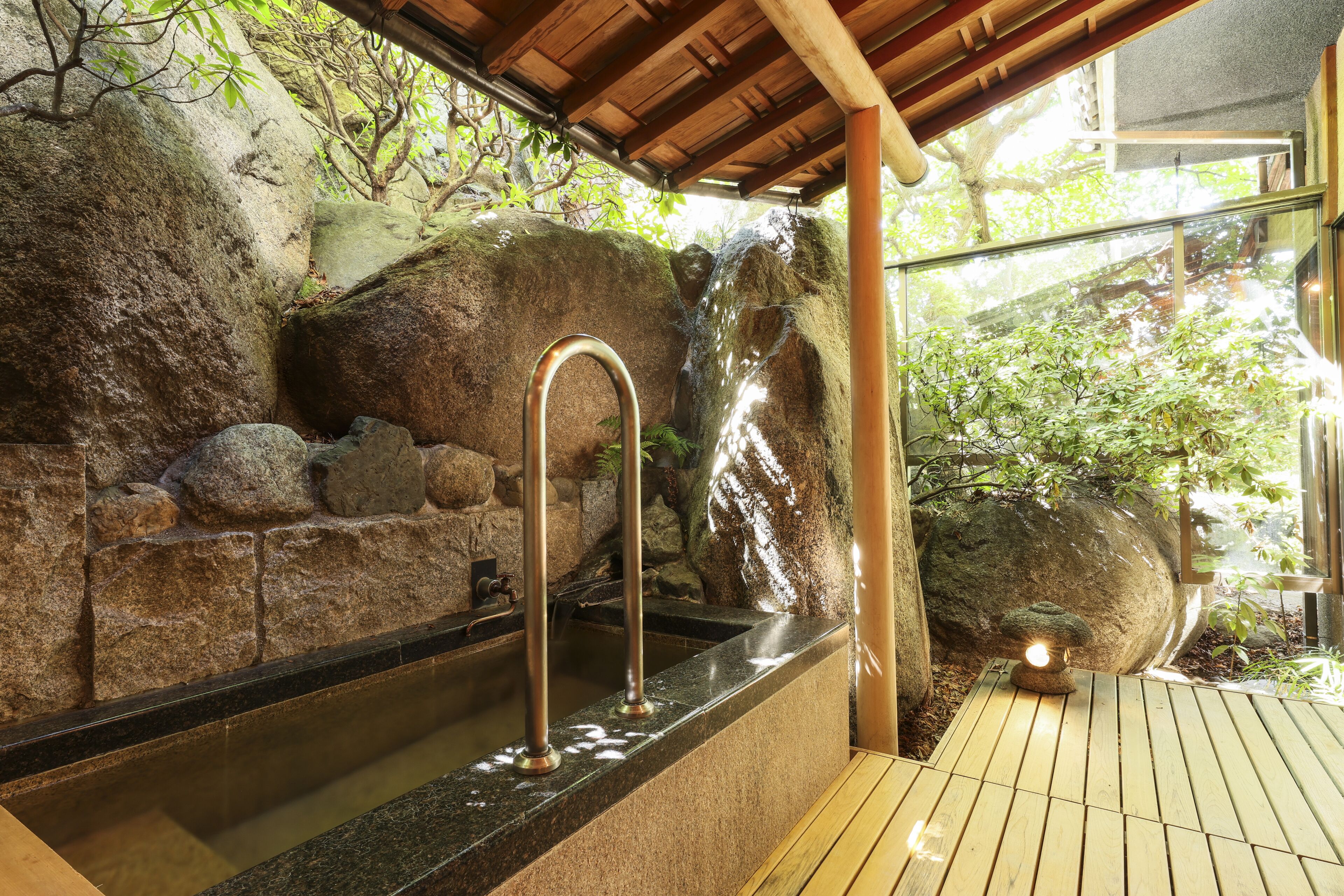 A stone wall with a water feature and a wooden deck.