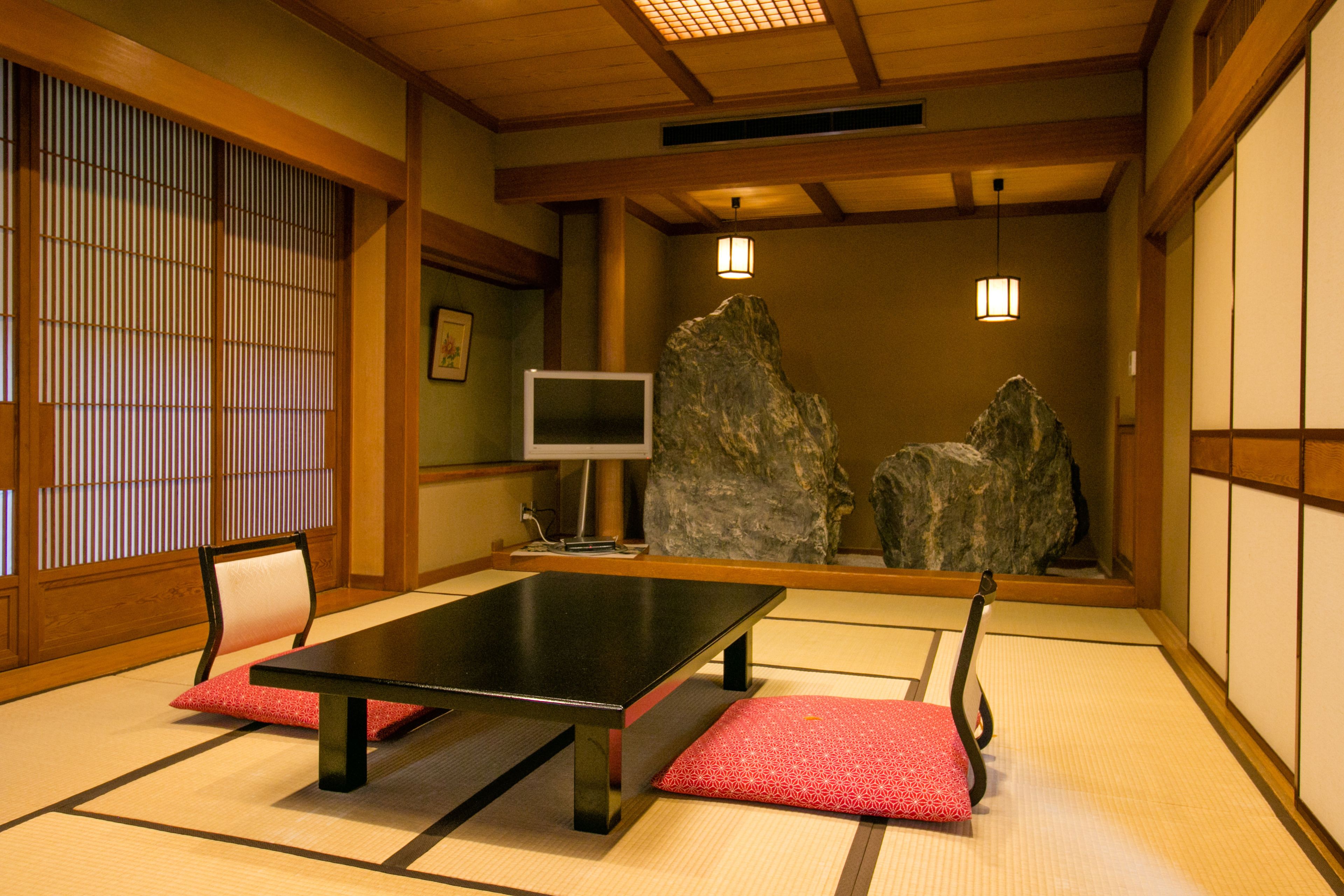 A traditional Japanese room with tatami flooring, a low table, and a TV.