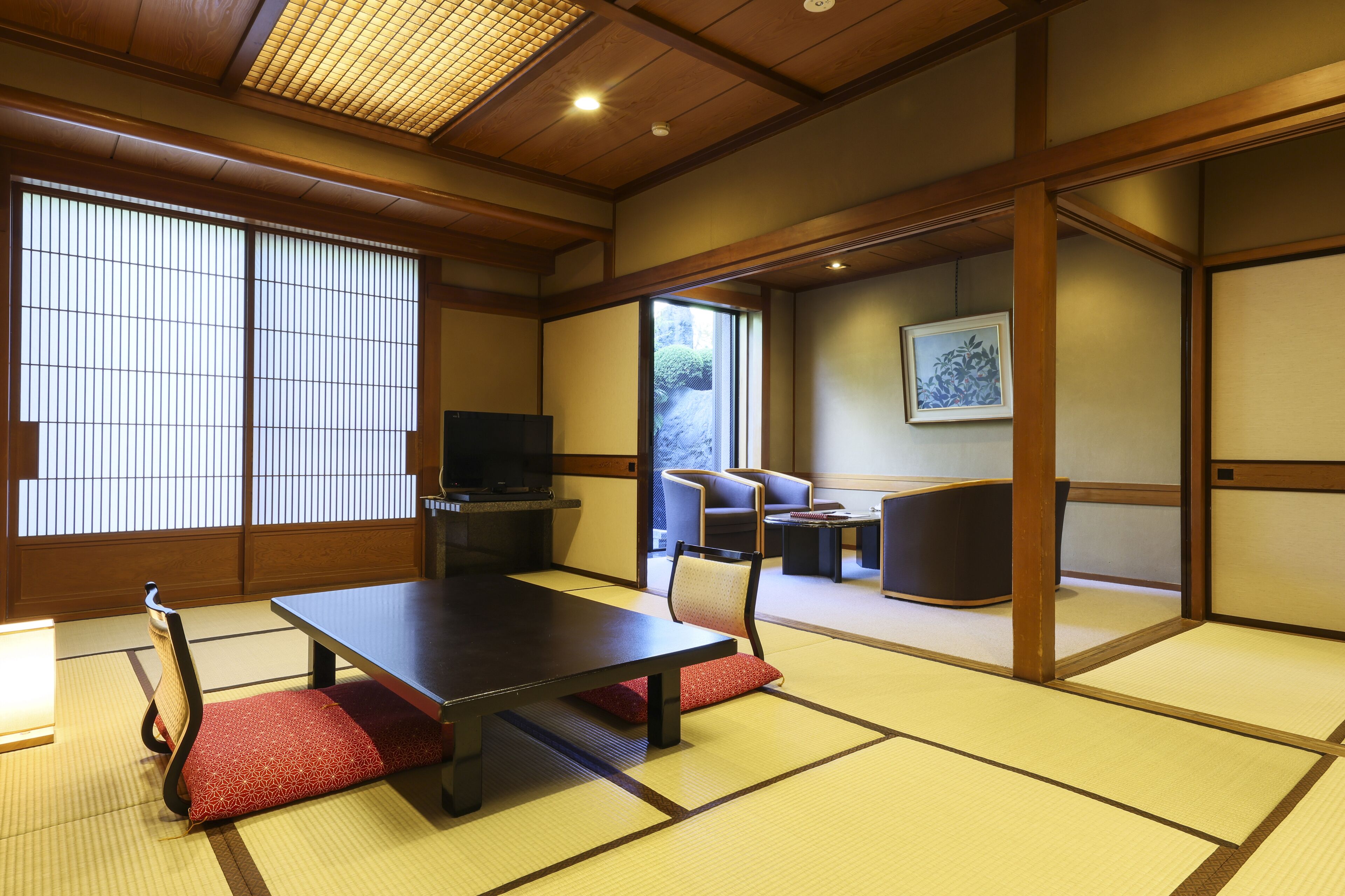 A traditional Japanese room with tatami flooring, a low table, and a sofa.